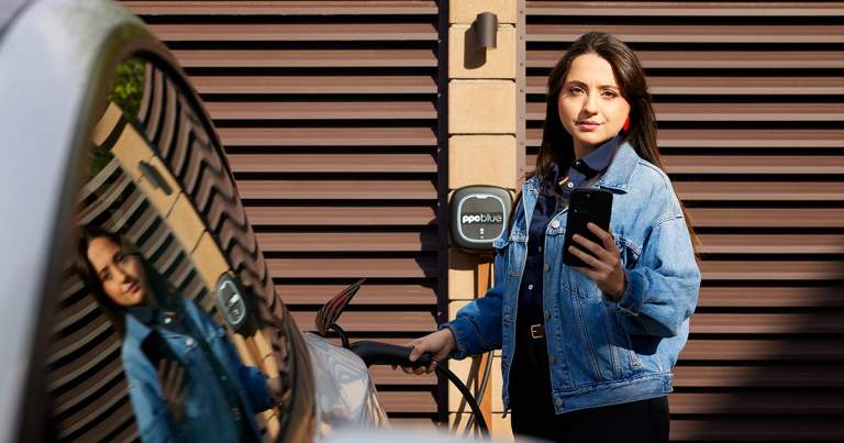 Femeie cu telefonul în mână încarcă mașina electrică la stația PPC blue