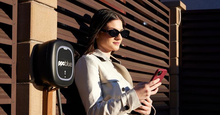 Femeie cu telefonul în mână lângă stația electrică PPC blue