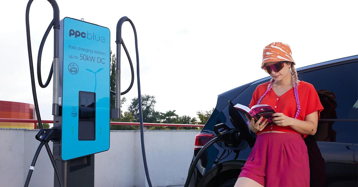 Femeie care citește și care așteaptă încărcarea mașinii electrice