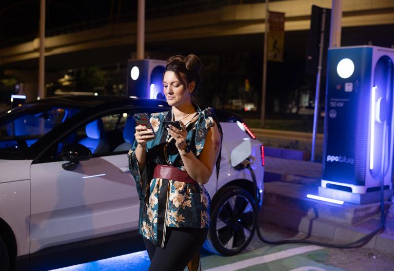 Femeie care folosește aplicația mobilă și stația de încărcare PPC blue