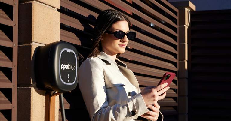 Femeie cu telefonul în mână lângă stația electrică PPC blue