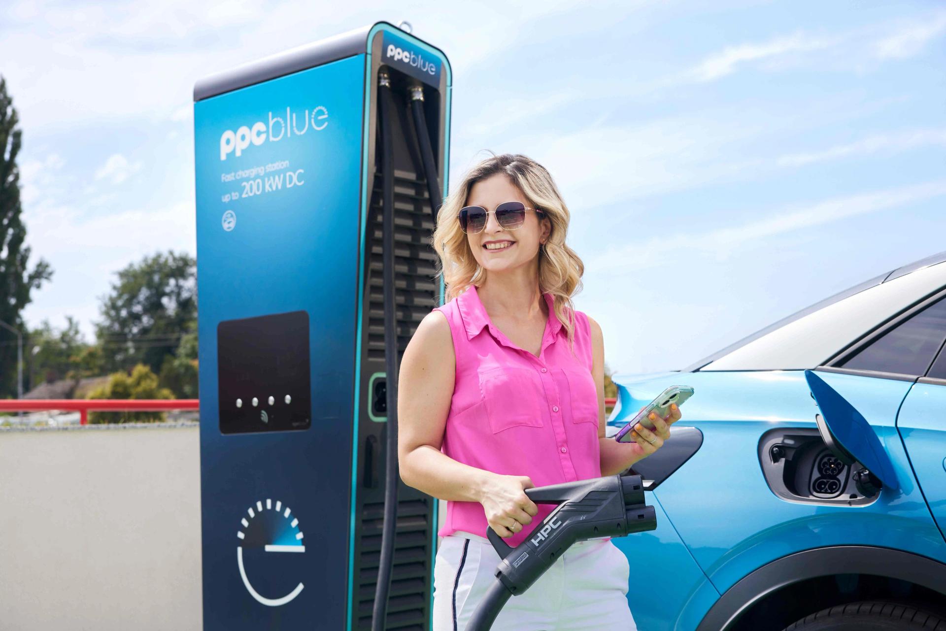 Femeie zâmbind încarcă mașina electrică la stația PPC blue