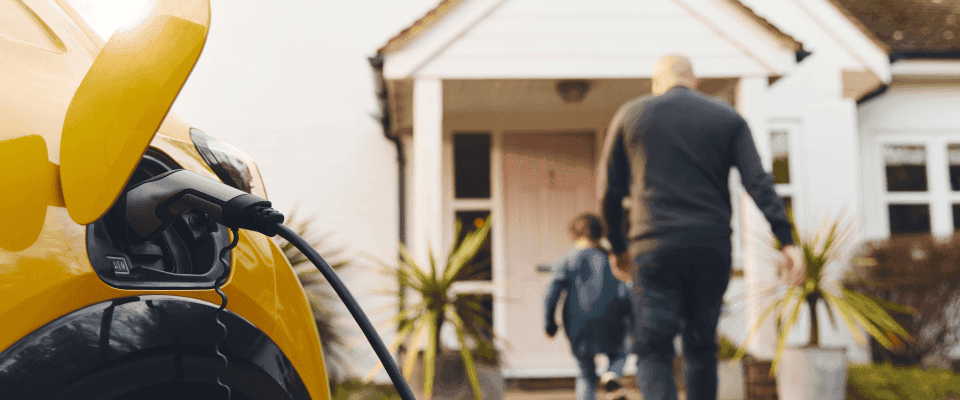 Mașină electrică conectată la stația de încărcare de acasă